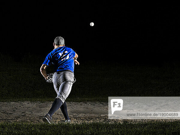 Young man with sports clothing throwing baseball at night