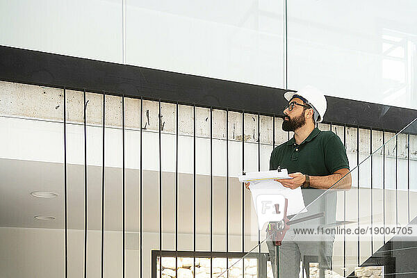 Architect examining and standing with document at construction site