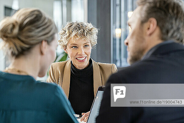 Happy businesswoman with colleagues sitting in office