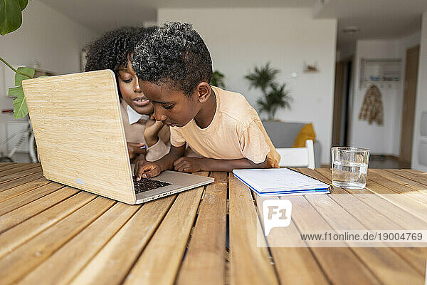 Mother with son studying on laptop at home
