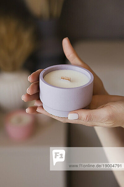 Hands of woman holding scented candle