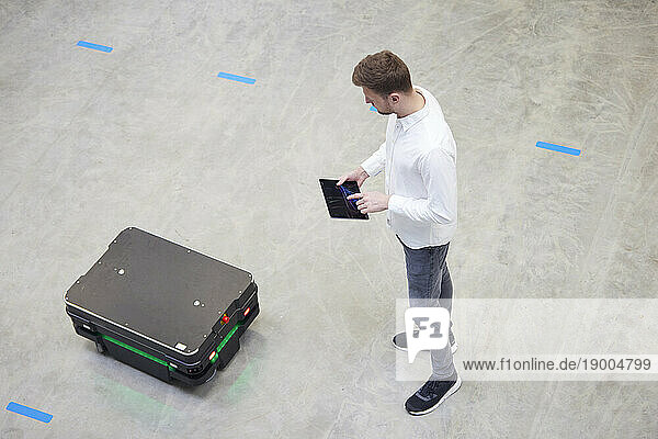 Engineer testing mobile robot through tablet PC in industry