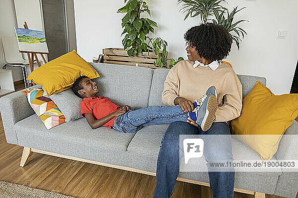 Happy mother with son lying on sofa at home