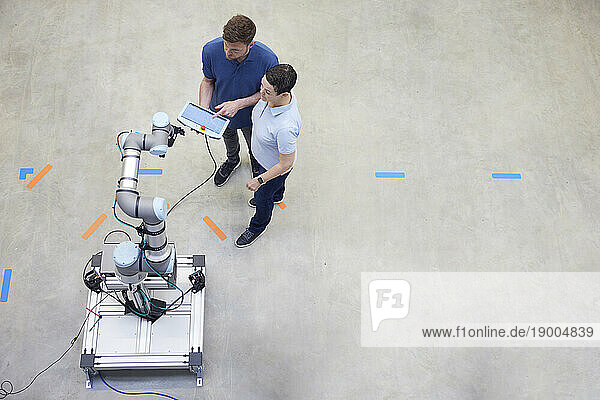 Engineers testing modern machine standing on floor in industry