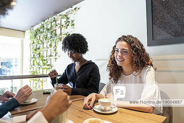 Happy young woman spending time with friends in cafe