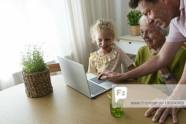 Father assisting family to use laptop at home