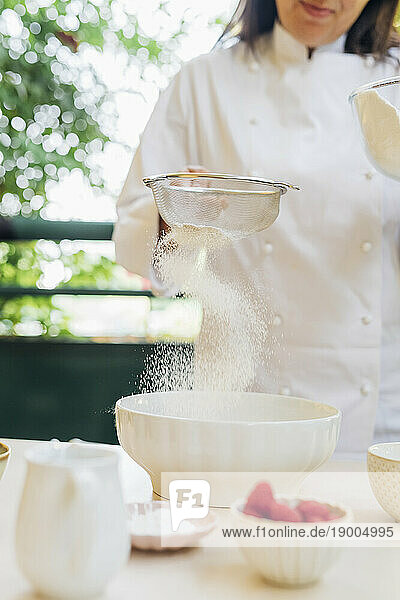 Chef sieving flour through siever