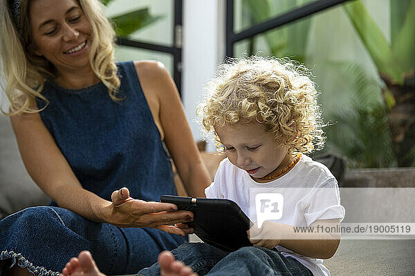 Smiling woman showing tablet PC to son at home