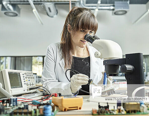 Scientist soldering circuit board in laboratory