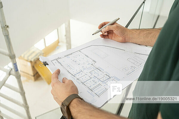 Hands of architect working on blueprint at contsruction site