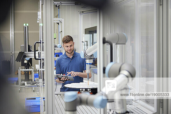 Technician examining modern robotic machine in industry