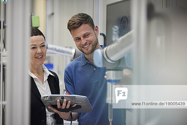 Smiling colleague explaining machine to manager in industry
