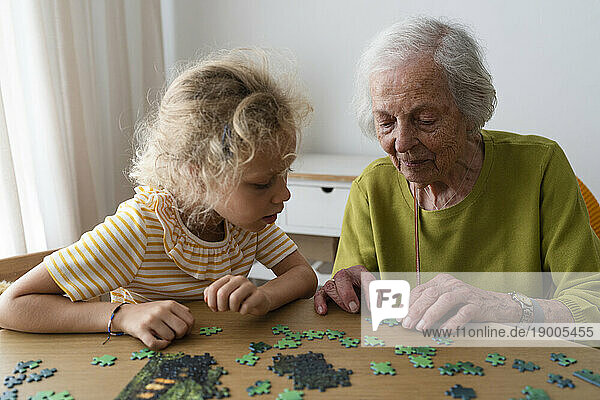 Grandmother and granddaughter solving jigsaw puzzle