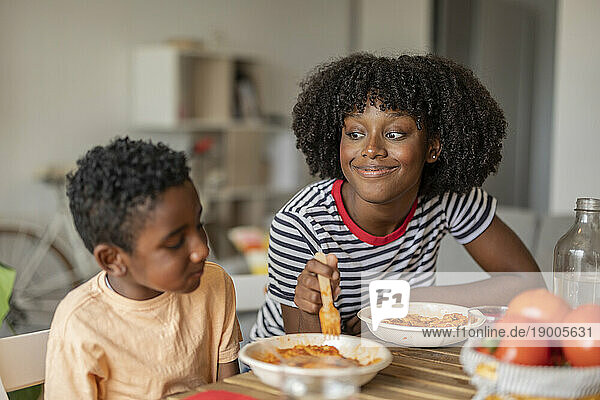 Smiling woman with son having food together at home