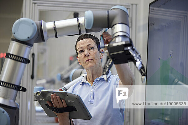 Engineer checking robotic arm holding equipment in industry