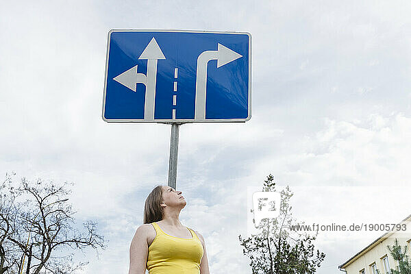 Woman standing under directional sign board