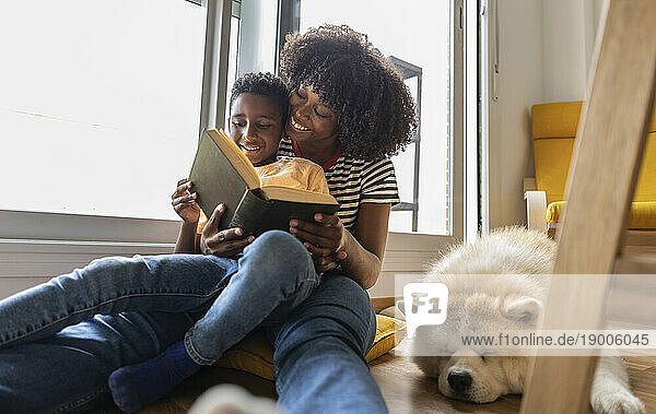 Happy mother and son reading book at home