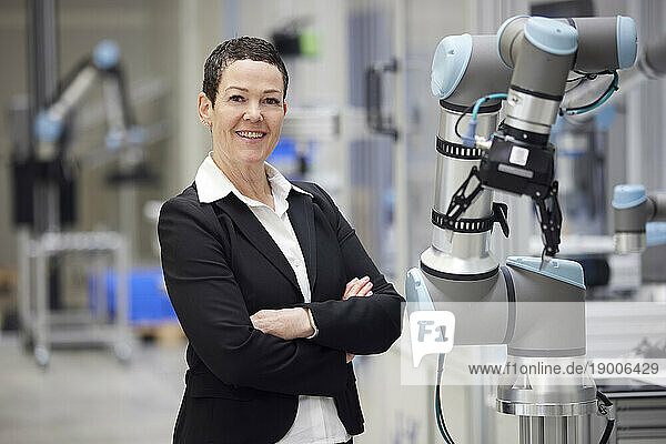 Confident smiling businesswoman standing with arms crossed in industry