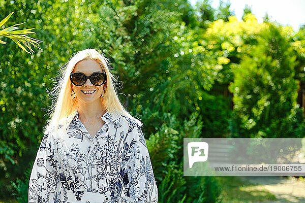 Porträt einer positiv lächelnden Frau im Garten oder Park
