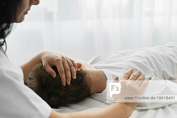 Eine Osteopathin behandelt einen Jungen  indem sie ihn massiert. Schönes Foto