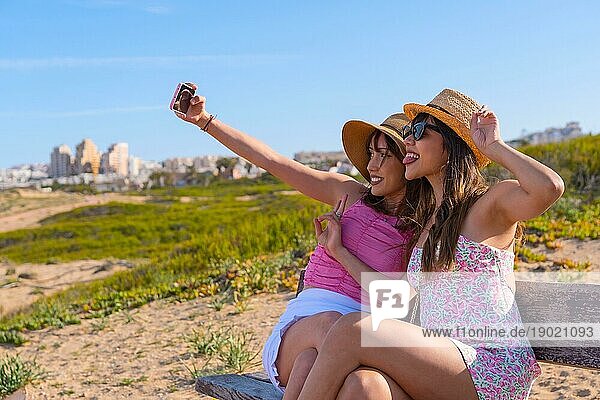 Freundinnen in Hut sehr glücklich am Strand Urlaub machen ein Selfie mit Telefon  Sommer Reise Freunde Freundschaft Konzept