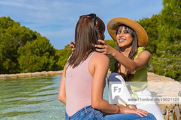 Weibliche Freunde haben Spaß im Urlaub in einem Park im Sommer  sitzen lächelnd an einem See  Lebensstil