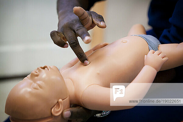 First aid training on a mannequin: cardiac massage on an infant.
