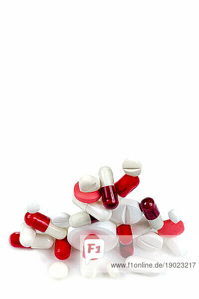 Red and white capsules and tablets stacked on a white background.
