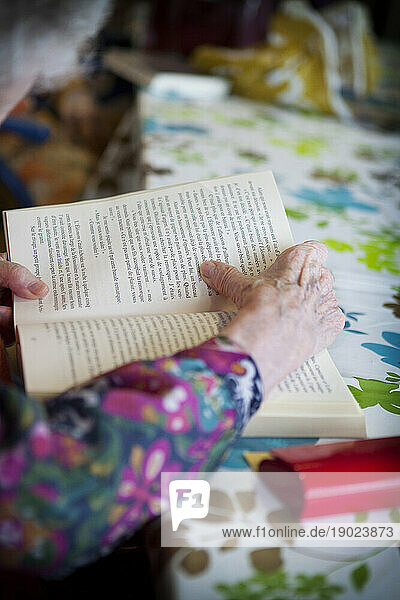 Elderly person reading a book in a retirement home.
