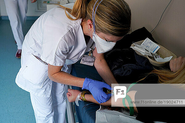 A nurse performs a blood test in the emergency room of a university hospital. A young girl was pricked by a needle  without her knowledge  during a party in a bar and fears an injection of drug. The blood sample will be analyzed and will serve as evidence in the event of a complaint being filed.