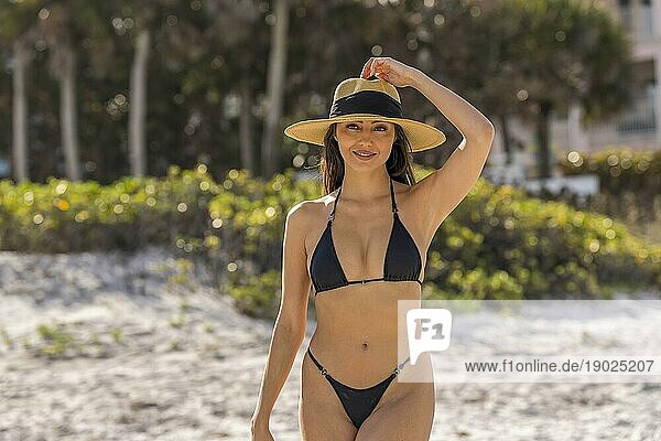 Ein wunderschönes Mixed race Bikinimodell genießt das Wetter draußen am Strand