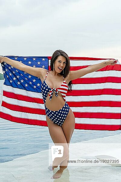 Porträt einer Frau  die einen patriotischen amerikanischen Bikini trägt und eine amerikanische Flagge hält
