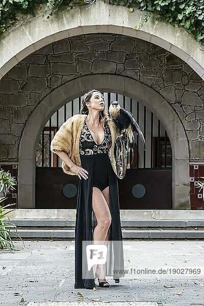 Eine wunderschöne Hispanic Brunette Modell posiert im Freien mit einem Caracara Vogel im Freien auf einer Hazienda