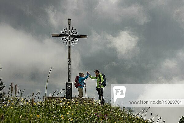 Junges Paar beim Bergsteigen  Wandern  Gipfelkreuz Brauneck  schlechtes Wetter  Nebel. Brauneck bei Lenggries  Isarwinkel  Oberbayern  Bayern  Deutschland  Europa
