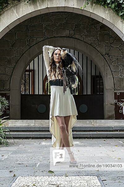 Eine wunderschöne Hispanic Brunette Modell posiert im Freien mit einem Caracara Vogel im Freien auf einer Hazienda