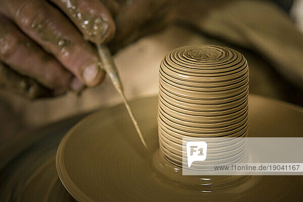 Close up of the hand of Daniel 'Chichi' Santander  renowned Cuban potter  applying fine detail to spinning pottery at El Alfarero Casa Chichi workshop. Trinidad  Sancti Spiritus  C