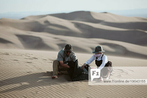 two adventurers take shelter from the whipping wind of the sand dunes