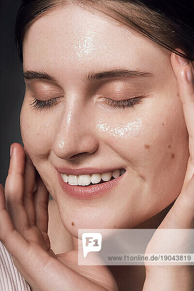 Face skin care. Woman applying a mask on clean hydrated skin portrait.