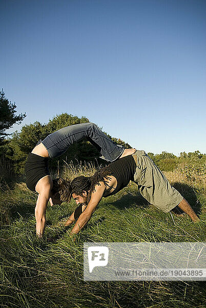 Man and woman practicing yoga in a field  Maine.