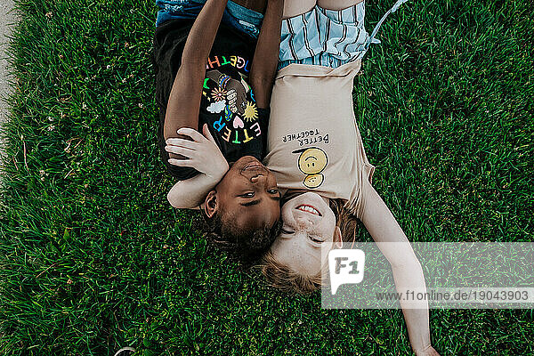 two girls laying in grass hugging and smiling