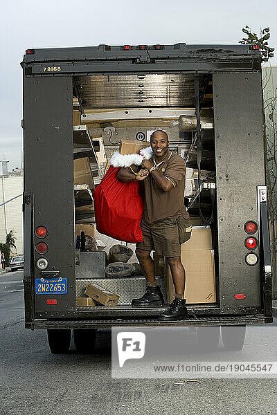 A delivery man lifts a bag in the back of a truck.