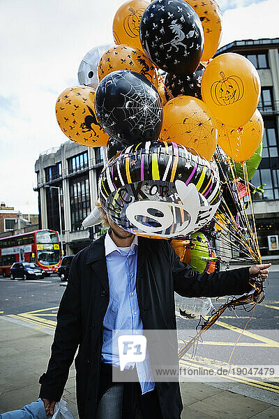 A man carrying colorful Halloween balloons.