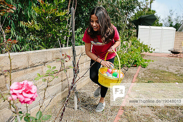 Girl smiles as she collects Easter eggs during an Easter egg hunt