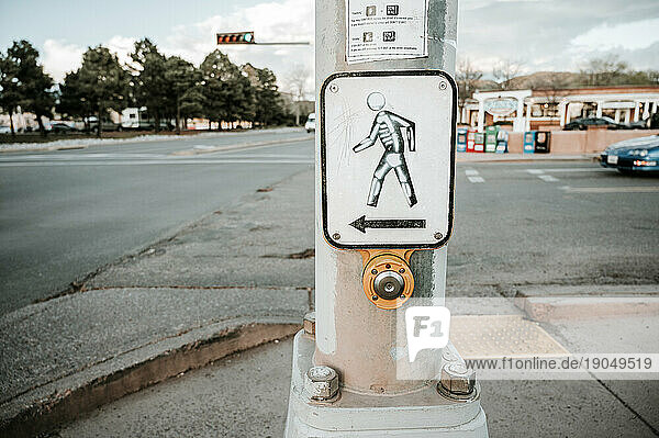 Walk signal sign with street art skeleton painted on by crosswalk