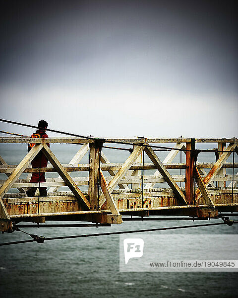 Side view of a person crossing the narrow footbridge  San Francisco  California.