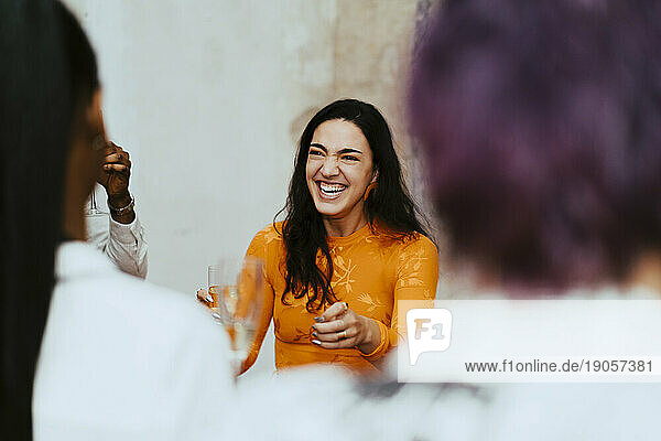 Fröhliche Geschäftsfrau lacht bei der Interaktion mit Kollegen während einer Veranstaltung im Kongresszentrum
