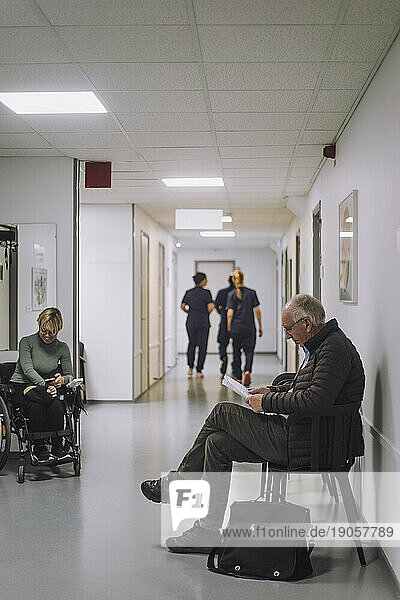 Seitenansicht eines älteren männlichen Patienten  der auf einem Stuhl im Wartezimmer eines Krankenhauses sitzt