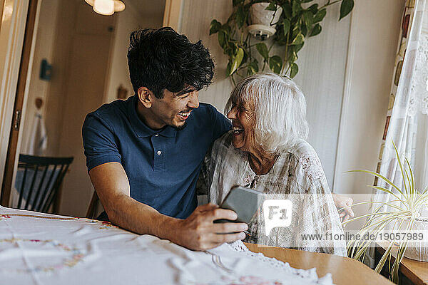 Glücklicher männlicher Pfleger mit lachender Seniorin zu Hause