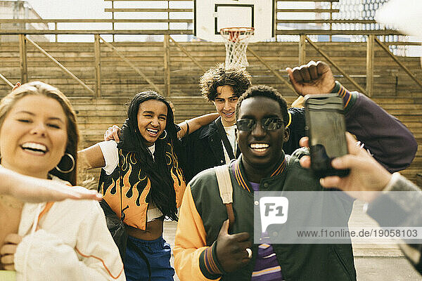 Fröhliche männliche und weibliche Freunde  die sich beim Tanzen auf dem Basketballplatz vergnügen