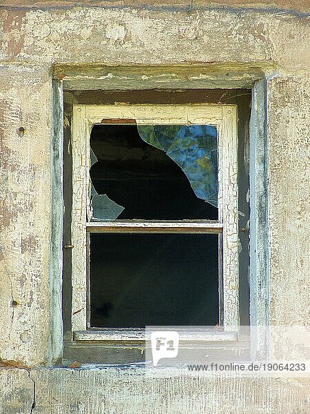 Hausdetail mit einem alten Fenster und einer zerbrochenen Scheibe